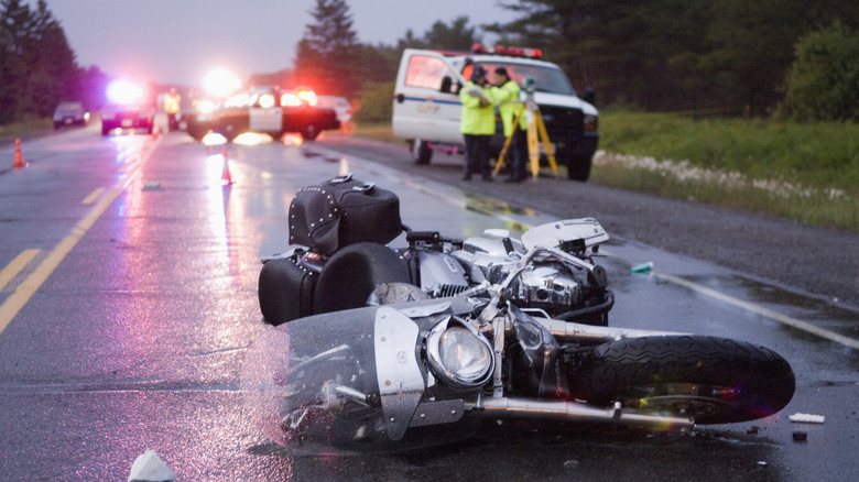 A motorcycle tipped on its side surrounded by police