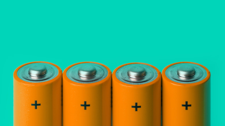 four AA batteries on a bright green background