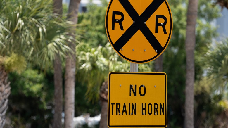 A railway crossing sign warns pedestrians and vehicles: NO TRAIN HORN