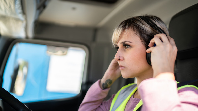 Female truck driver sitting inside her truck with headphones on.