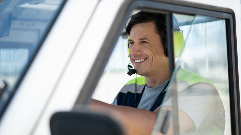 Male truck driver wearing a neon-colored headset inside his truck.