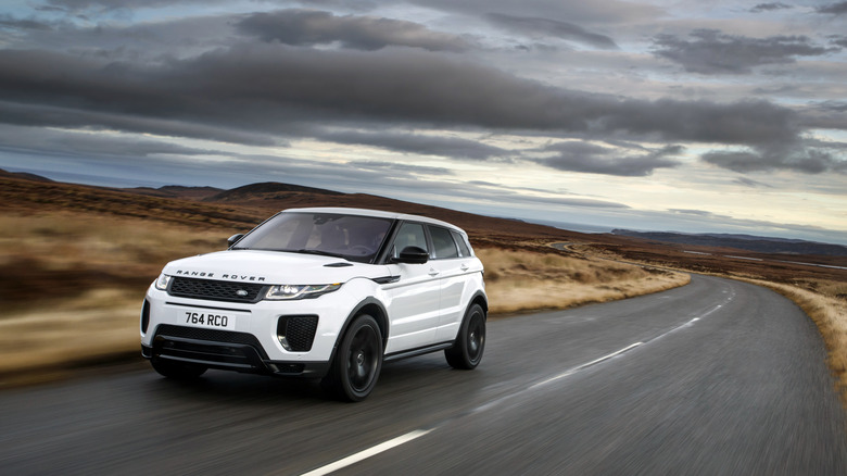 A white Range Rover Evoque on the move, front 3/4 view, overcast day