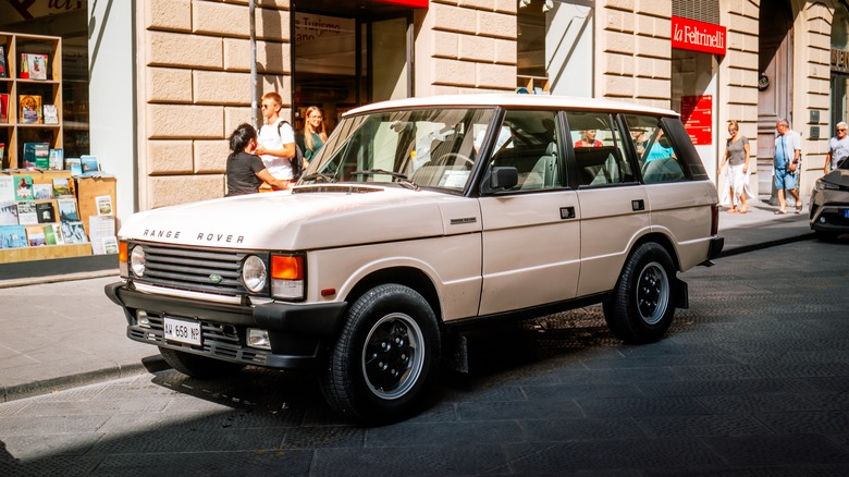 A front 3/4 view of a beige Range Rover Classic parked on a street