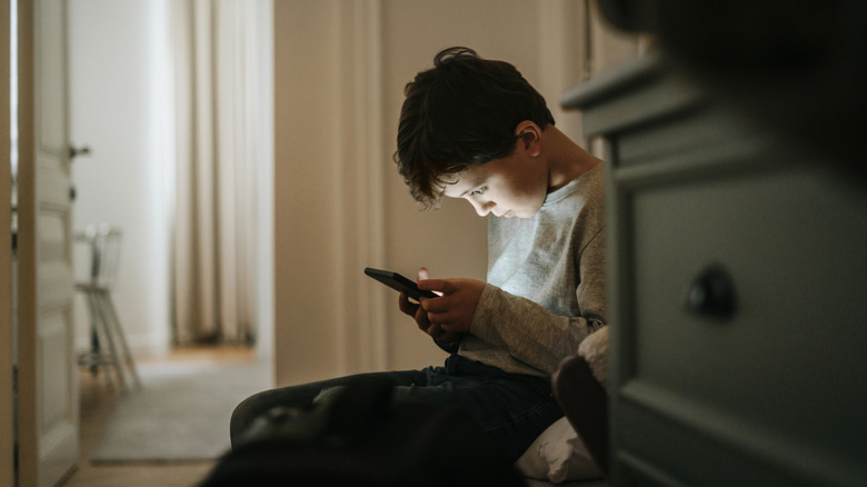 boy using smartphone dark room