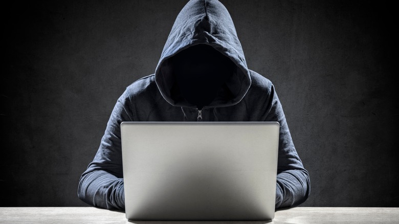 hooded computer hacker at work