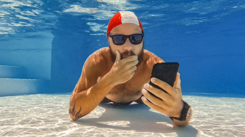 person underwater looking at smartphone