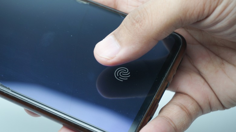 A person holds their thumb over an in-screen fingerprint scanner