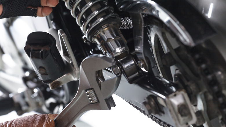 A mechanic working on a motorcycle with a wrench