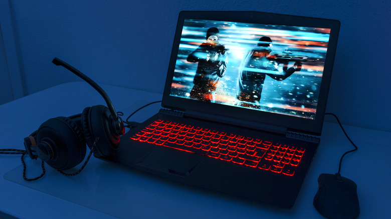 gaming laptop in dark room with headset and mouse