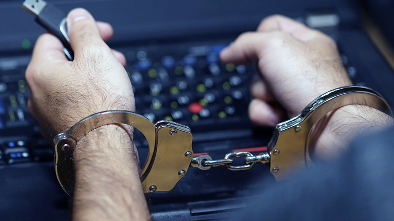 Hands in handcuffs over laptop