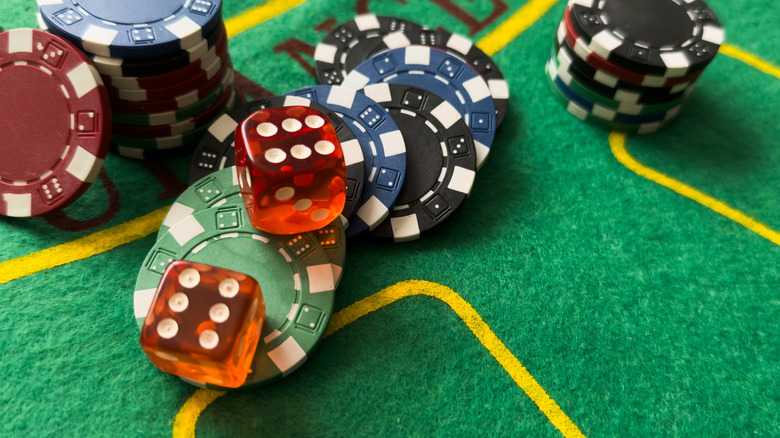 Rolling red dice on a casino table with chips.