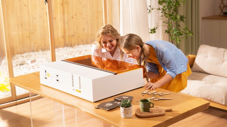 Two people using xTool S1 laser engraver on table