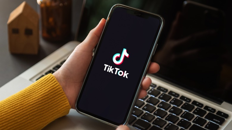 Hand holding a phone with TikTok open