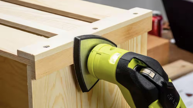 Person using multi-tool sanding attachment on wood