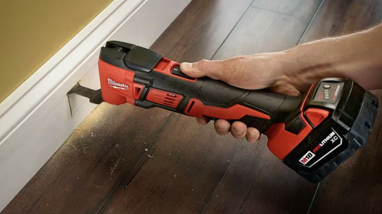 Person using an oscillating tool on a baseboard