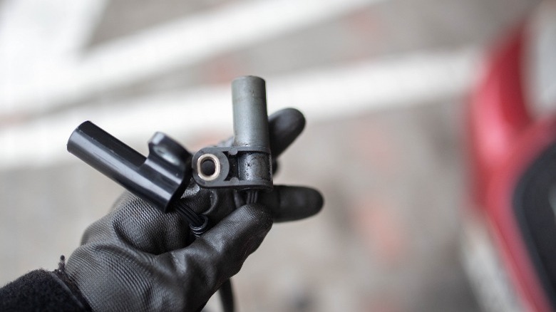 A crankshaft position sensor in a gloved hand