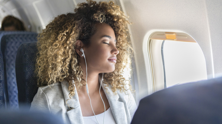 woman using apple earpods on plane