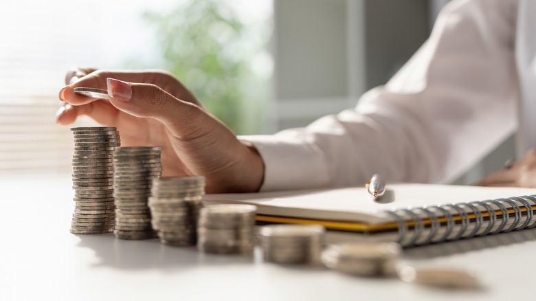 hand stacking coins on desk