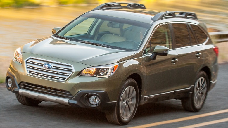 2015 Subaru Outback In Green Driving On A Paved Road