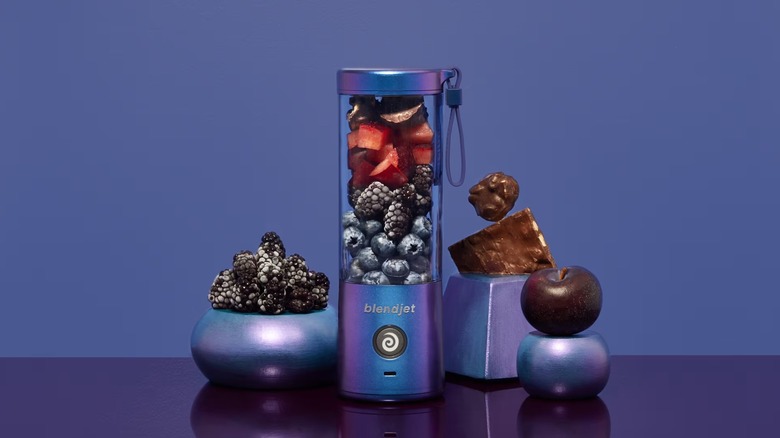 Black personal sized blender filled with chocolate, berries, and ice