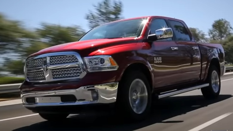 A red 2014 Ram 1500 EcoDiesel truck driving down a road.