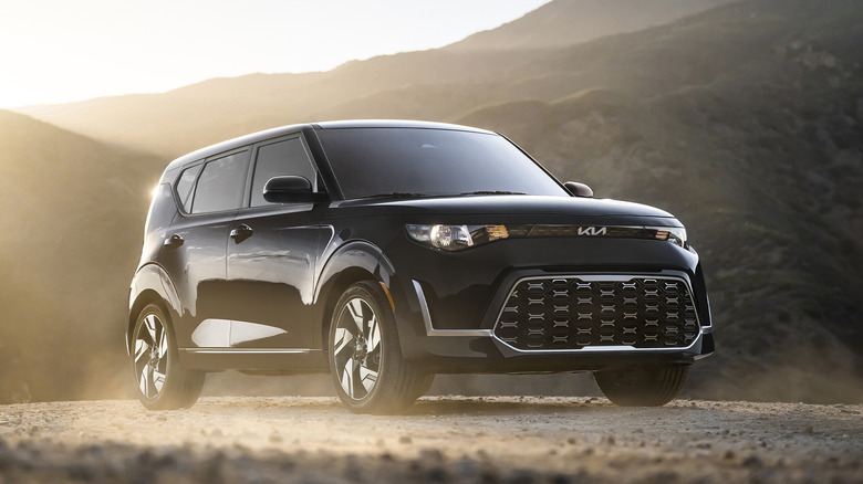 Black Kia Soul parked in mist on dirt road with mountains in background