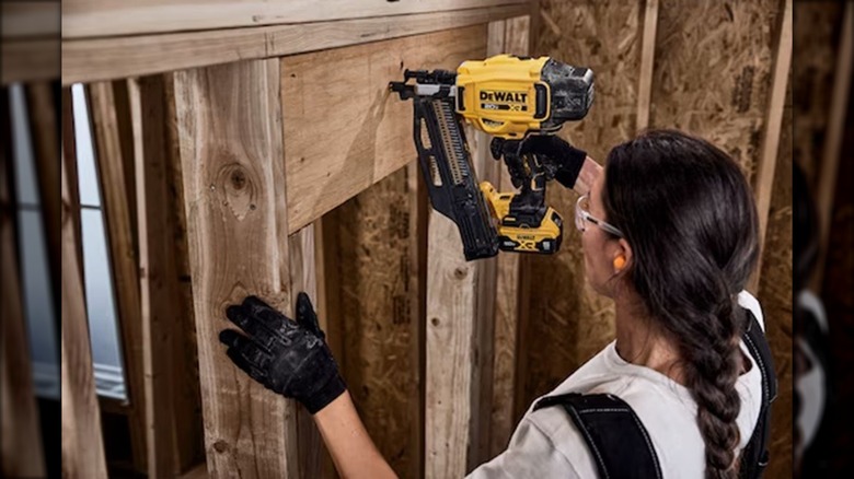 A carpenter using a DeWalt Framing Nailer to install a door header.