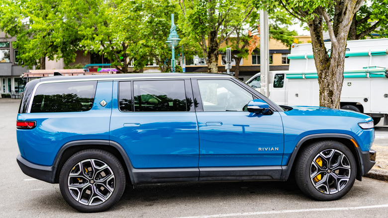 Side profile of a Rivian electric SUV in orange color.