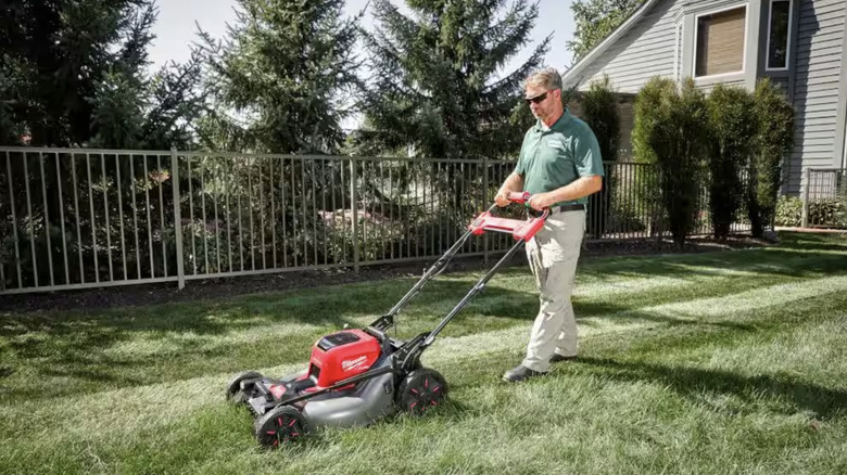 Man using electric lawn mower on yard