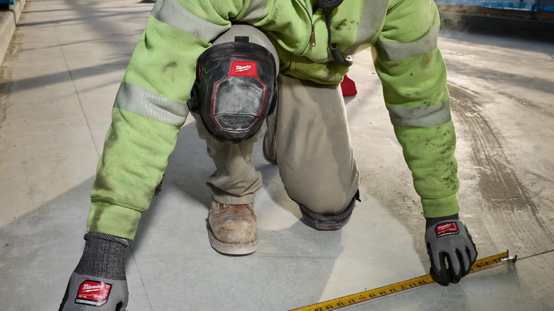 man using measuring tape on floor