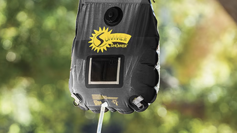 Solar shower bag hanging from tree near river