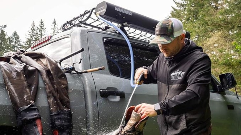 Man hosing boots with outdoor shower 