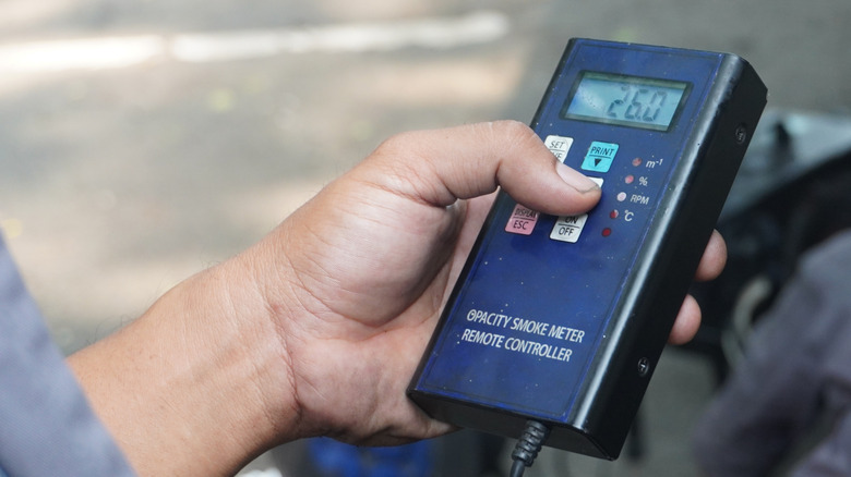 A hand holding a car emissions testing device