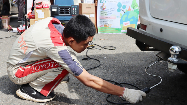 A technician conducting an emissions test from behind the vehicle