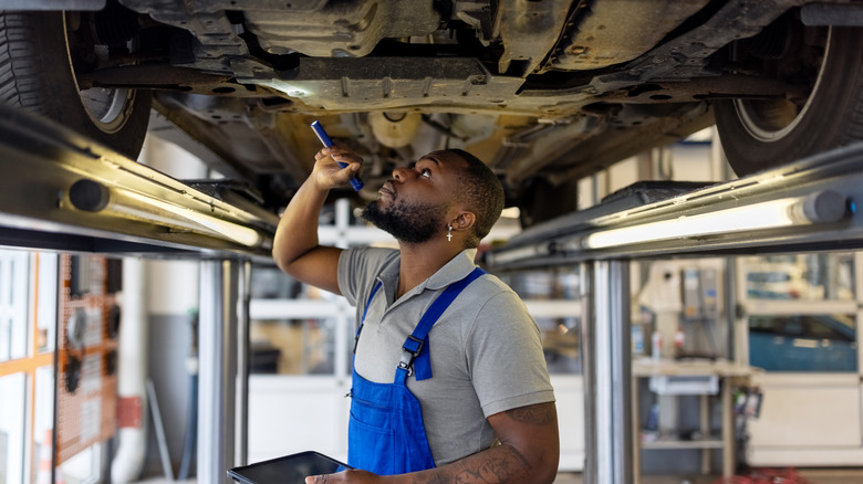 A mechanic inspecting the underside of a car