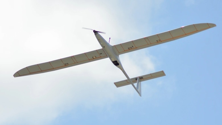 The K1000ULE UAS, from below, flying before clouds and a blue sky