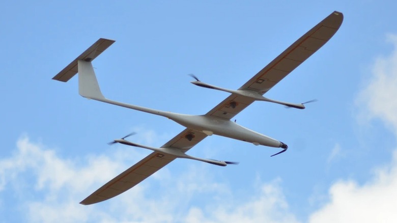 The K1000ULE VTOL UAS, from below, flying before clouds and a blue sky