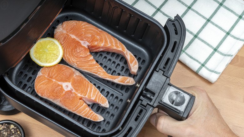 person inserting salmon into air fryer