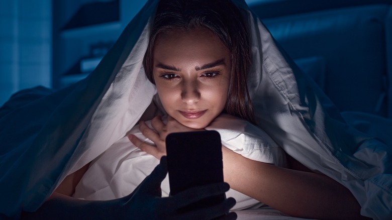Girl using her iPhone in bed