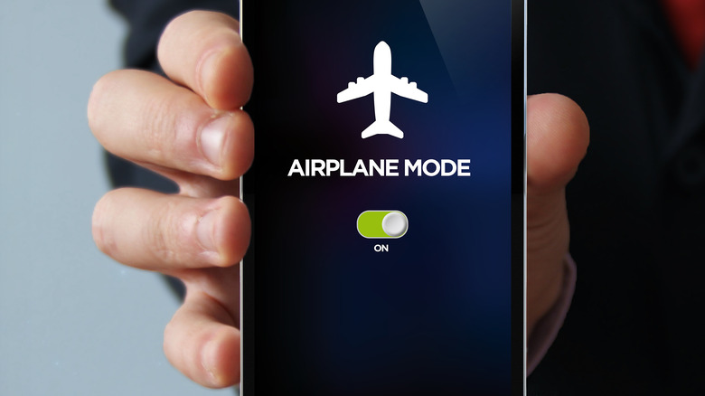 Hand holding Smartphone displaying Airplane Mode