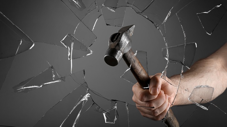 Man breaks glass with a hammer