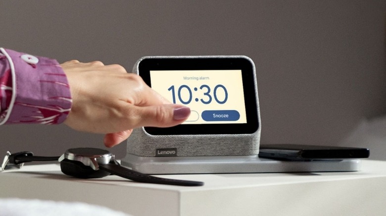 Woman's hand reaching over to snooze Lenovo Smart Clock