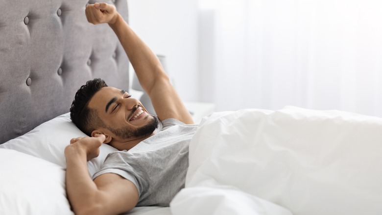 Man stretching in bed in the morning