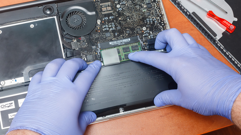 electronics repairperson taking out a Mac battery