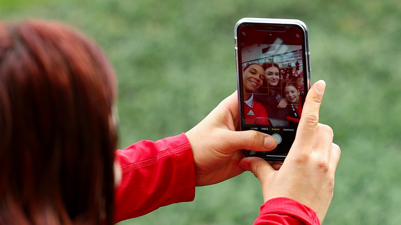 person taking iphone group selfie