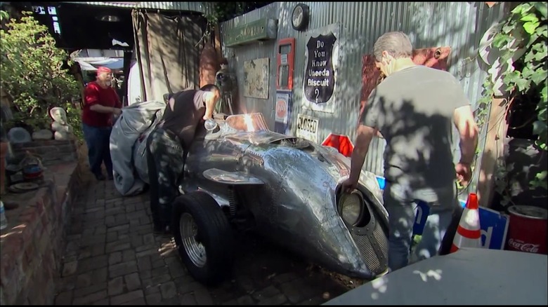 Three guys looking at a homemade motrocycle