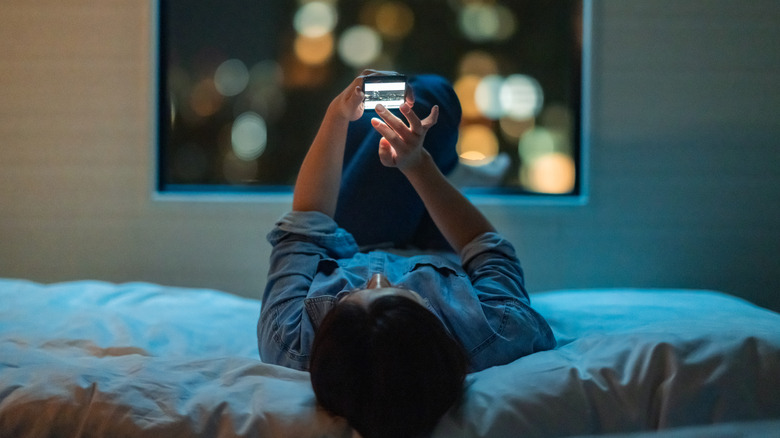 person using phone in dark bedroom