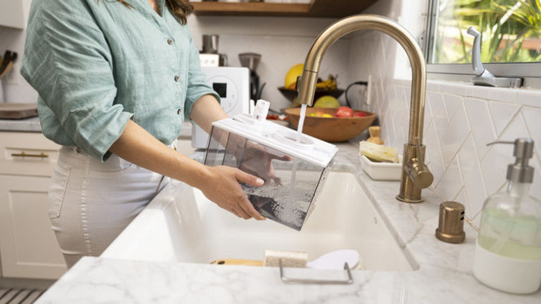 Woman putting clean water into a humidifier water tank