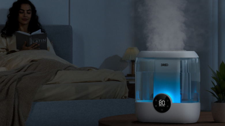 Working humidifier in the bedroom with a woman reading a book in the background