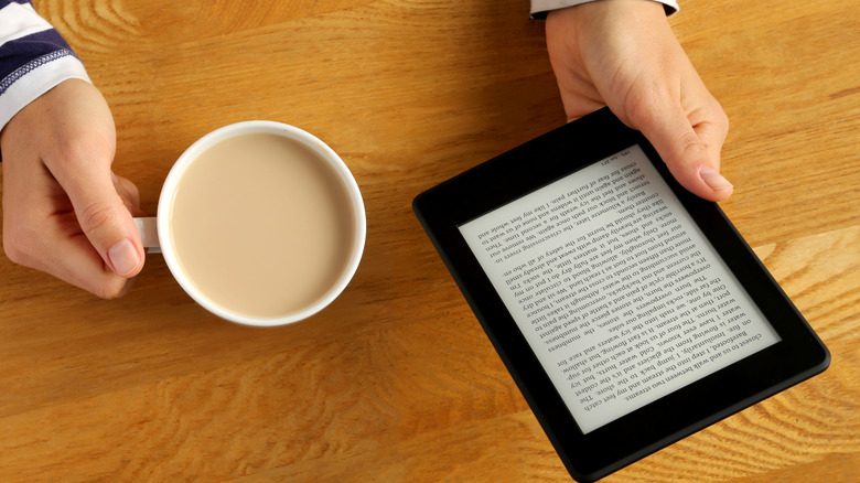 hand with coffee reading Kindle